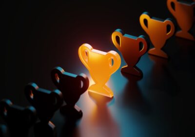 Trophy symbol glowing amid black trophy symbols on black background.