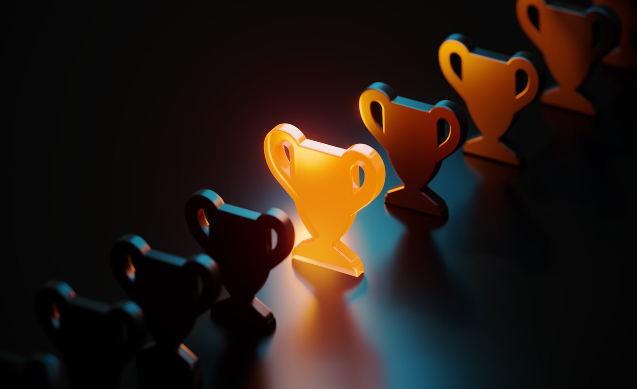 Trophy symbol glowing amid black trophy symbols on black background.