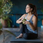 Portrait of a fit Latin American woman drinking a green detox smoothie at the gym - healthy lifestyle concepts