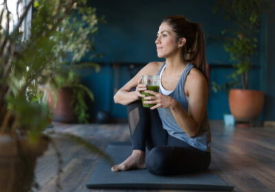 Portrait of a fit Latin American woman drinking a green detox smoothie at the gym - healthy lifestyle concepts